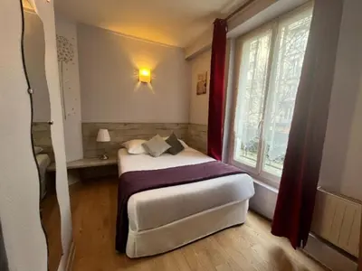 Un ou plusieurs lits dans un hébergement de l'établissement Alliance Hôtel Paris